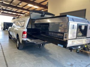 Extendobed slideout system with lockable diamond-plate compartments and mesh containment shelvin